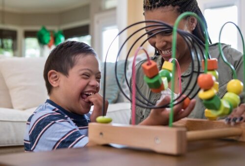When the mid adult mom and her special needs son play in the living room, they laugh together.